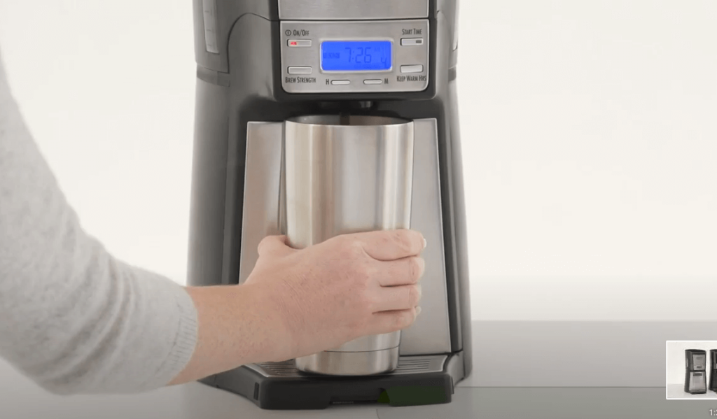 A man holding his cup against Hamilton Coffee Machine. Carafe free design is really important feature for Hamilton Beach BrewStation Review