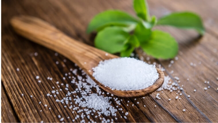 Stevia granules on a wooden spoon and wooden ttable