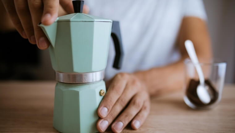 Man using Moka pot coffee maker to create a fresh and delicious cup of espresso