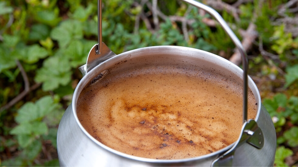 Close-up photography of cowboy coffee brewing on a stove outside in the forest