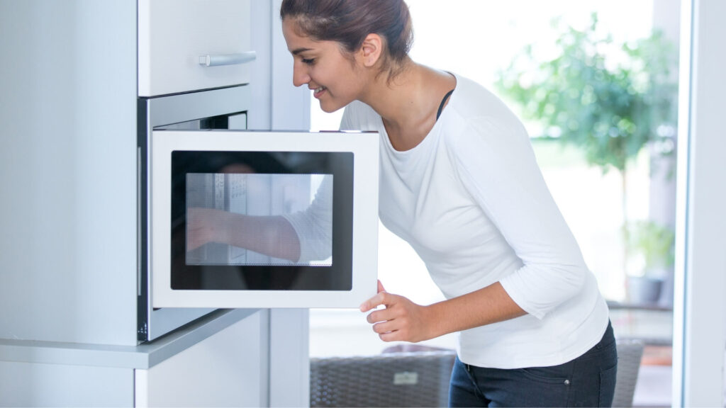 A woman warming her coffee in microwave