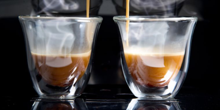 Two glass espresso cup filled with freshly brewed and hot espresso